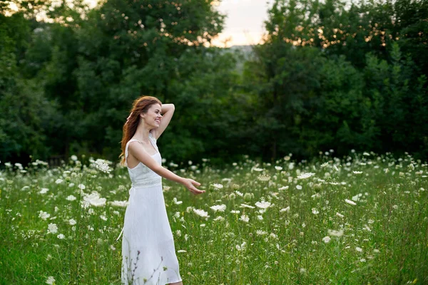 하얀 드레스를 입고 자연의 꽃 이 핀 들판에서 자유 여름을 보내는 여성 — 스톡 사진
