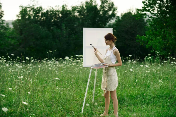 Женщина-художник рисует на мольберте на природе — стоковое фото