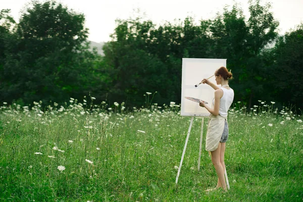 Kobieta artysta maluje na sztalugach w krajobrazie natury — Zdjęcie stockowe