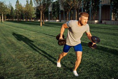 Parktaki atletik adam egzersiz dambılları