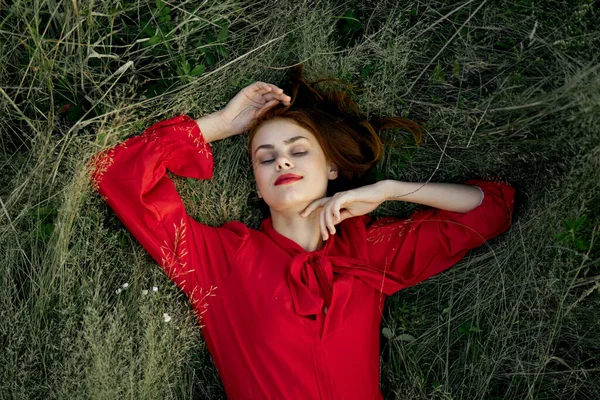 Γυναίκα με κόκκινο φόρεμα βρίσκεται στο γρασίδι ελευθερία φύση καλοκαίρι — Φωτογραφία Αρχείου