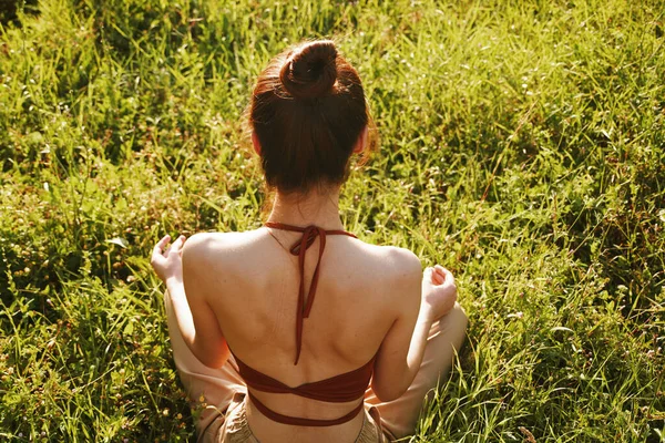 Kvinna på fältet sitter på gräset meditation vila — Stockfoto