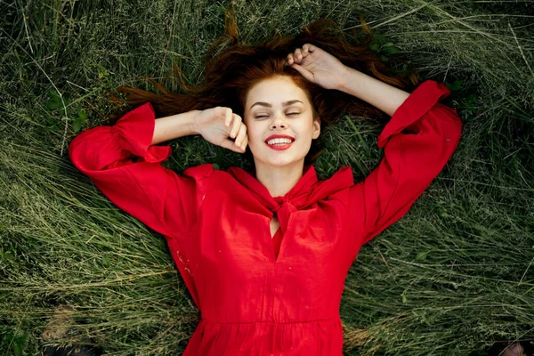 Femme gaie dans une robe rouge se trouve sur l'herbe vue de dessus — Photo
