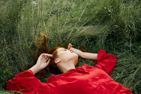 Mujer en vestido rojo se encuentra en la libertad encanto hierba — Foto de Stock