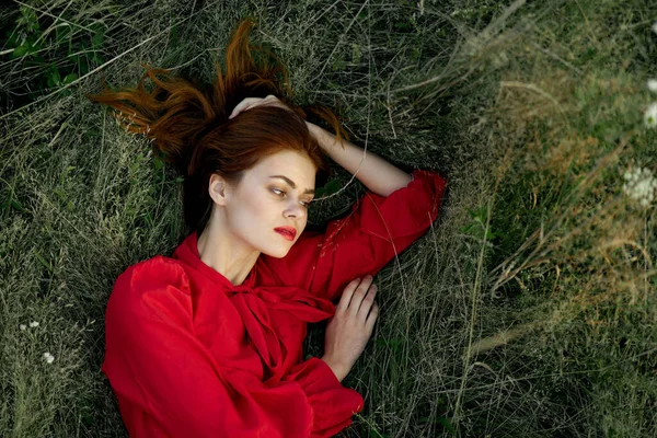 Όμορφη γυναίκα με κόκκινο φόρεμα βρίσκεται στο γρασίδι ήλιο καλοκαίρι φύση — Φωτογραφία Αρχείου