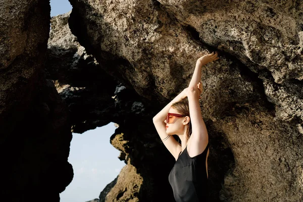 Femme en maillot de bain noir posant près des rochers océan exotique — Photo