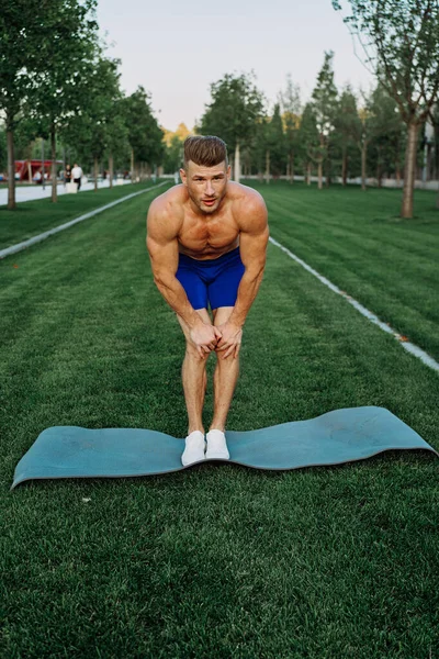 Hombre deportivo en pantalones cortos en el parque haciendo ejercicio al aire libre —  Fotos de Stock