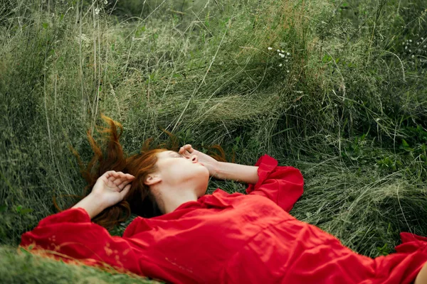 Femme en robe rouge repose sur l'herbe charme liberté — Photo