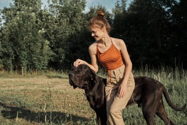 Yazın tarlada köpek dostluğuyla oynayan bir kadın.