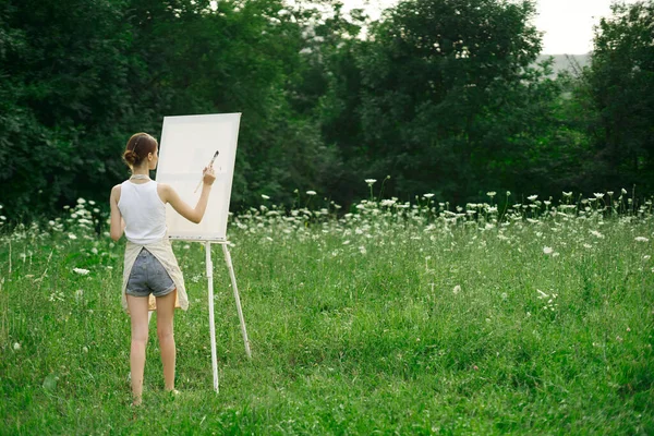 Önlüklü kadın ressam palet boyası doğayı resmediyor. — Stok fotoğraf