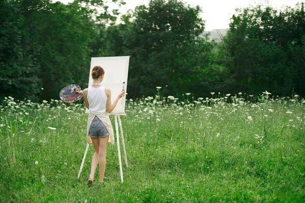 Önlüklü kadın ressam palet boyası doğayı resmediyor. — Stok fotoğraf