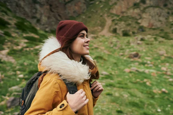 Mulher em uma jaqueta amarela com uma mochila nas montanhas viagem aventura — Fotografia de Stock