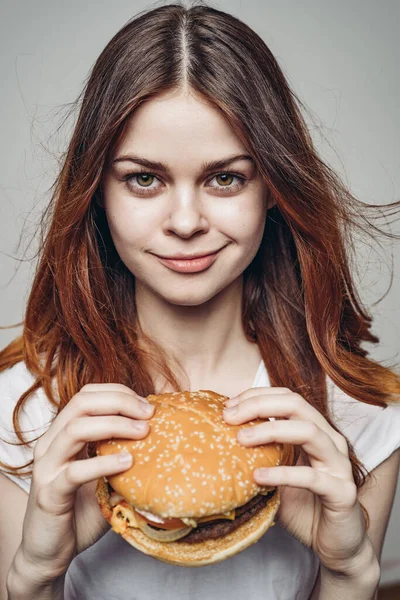 Femme avec un hamburger dans ses mains une collation fast food close-up — Photo