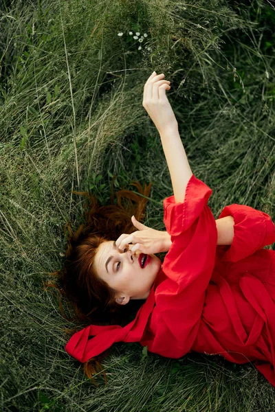 Nő piros ruhában fekszik a füvön friss levegő természet szabadság — Stock Fotó