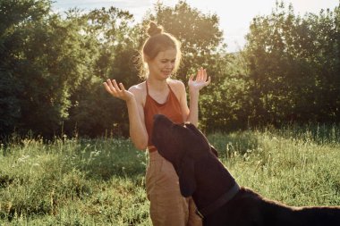 Yazın bir tarlada köpekle oynayan neşeli bir kadın.