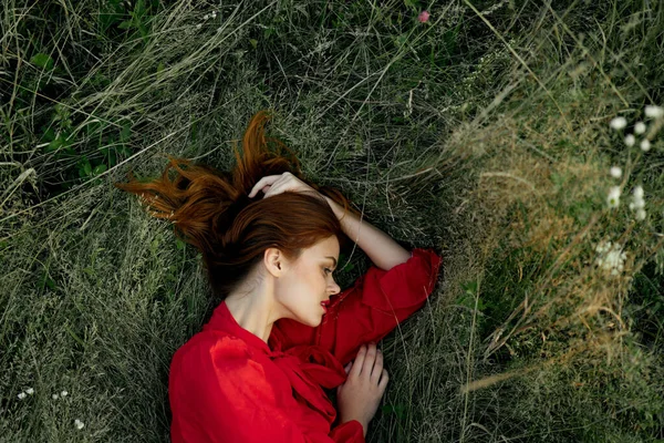Όμορφη γυναίκα με κόκκινο φόρεμα βρίσκεται στο γρασίδι ήλιο καλοκαίρι φύση — Φωτογραφία Αρχείου