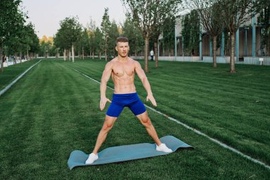 Mavi şortlu atletik adam parkta çalışıyor.