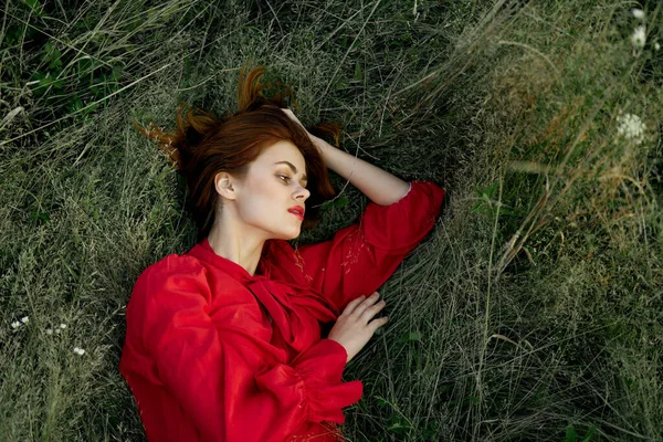 Γυναίκα με κόκκινο φόρεμα βρίσκεται στο γρασίδι ελευθερία φύση καλοκαίρι — Φωτογραφία Αρχείου