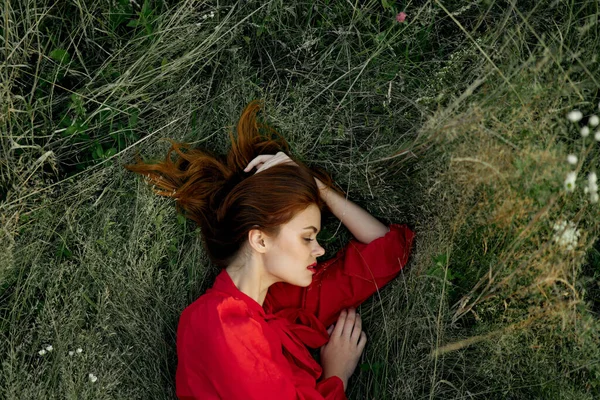 Pretty woman in red dress lies on the grass sun summer nature — Stock Photo, Image