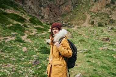 Sırt çantalı bir kadın dağlarda yürüyüş yapıyor.