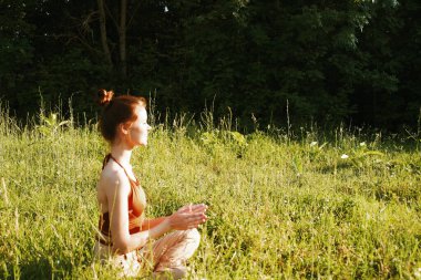 Çimlerde oturan kadın meditasyonda dinleniyor.