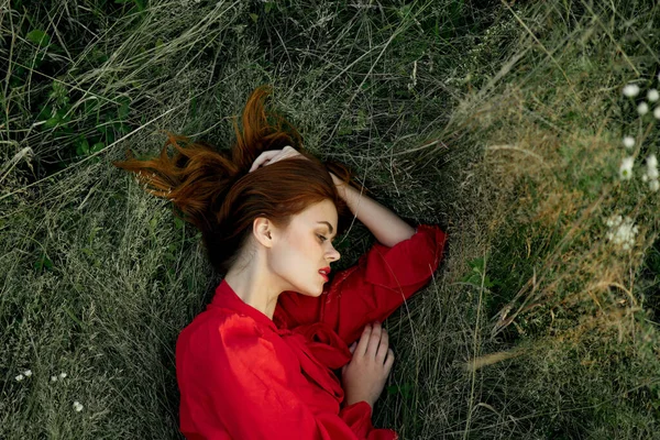 Hübsche Frau im roten Kleid liegt auf dem Gras Sonne Sommer Natur — Stockfoto
