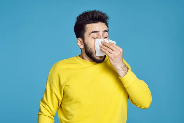 Чоловік в жовтому светрі проблеми зі здоров'ям емоції синій фон — стокове фото