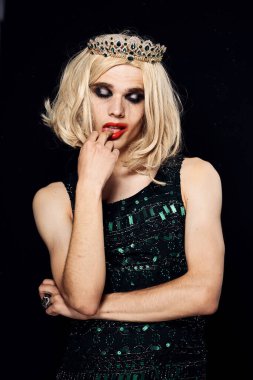 Kadın peruğu ve kadın elbisesi giyerek makyaj yapan bir adam.