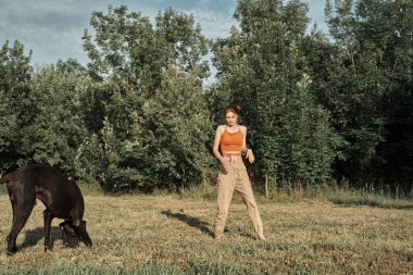 Dışarıda büyük siyah bir köpekle oynayan bir kadın. Eğlenceli bir arkadaşlık.