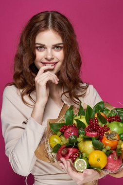 Neşeli, parlak makyajlı, çekici bir kadın. Bir buket meyveli arka plan.