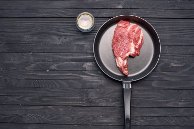 Kızartma tavasında biftek. Mutfak ahşap masa.