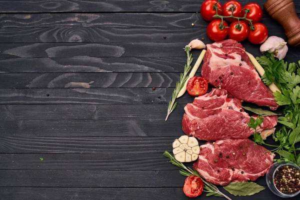 Meat on wooden board vegetables and ingredients for cooking wooden background — Stock Photo, Image