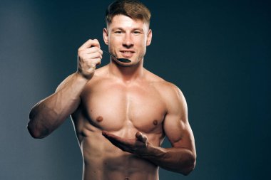 Gövdesi kaslı, spor yapan koyu renk arka planı olan bir adam.