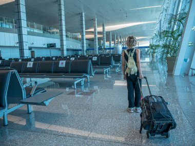 Coronavirüs salgını sırasında boş bir havaalanı. Sırt çantası ve bagajı olan küçük bir turist uçağa biner..
