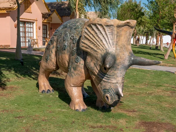 Turist bungalovlarının önündeki çimenlikte gerçek boyutta dinozor heykeli.