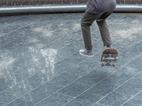 Adolescente pulando em um skate. O skate está girando. Close-up. Foco suave seletivo. — Fotografia de Stock