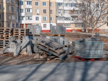 Ahşap paletler üzerinde gri bir kaldırım taşı bir sokak tadilatı sırasında dışarıda durur..
