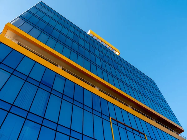 Wysoki, atrakcyjny budynek z niebieską szklaną fasadą. Widok dolny. — Zdjęcie stockowe