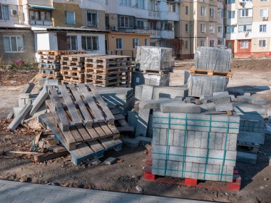 Ahşap paletler üzerinde gri bir kaldırım taşı bir sokak tadilatı sırasında dışarıda durur..