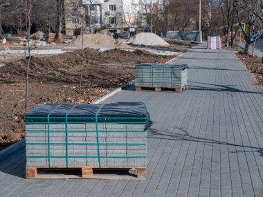 Ahşap paletler üzerinde gri bir kaldırım taşı bir sokak tadilatı sırasında dışarıda durur..