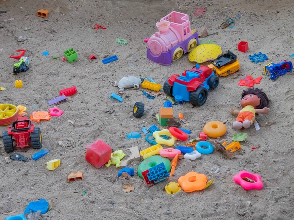 Dzieci wielokolorowe plastikowe zabawki są rozrzucone na piasku. — Zdjęcie stockowe