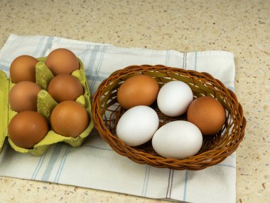 Karton kutuda tavuk yumurtası ve klasik masada hasır sepetin içinde. Boşluğu kopyala.