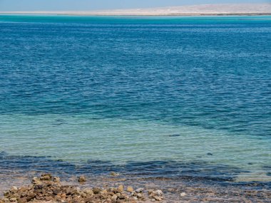 Dalgaların çekildiği güzel bir sahil şeridi. Mavi gökyüzüne karşı mavi deniz.