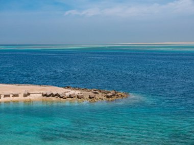 Güneşli bir günde, dalgaların çekildiği güzel ve korunmasız bir deniz kıyısı..