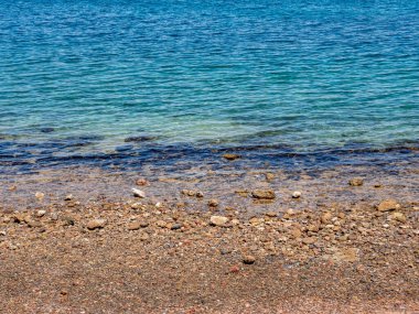Dalgalar çekildiğinde çıplak kayalık deniz kıyısı. Güneşli gün ve mavi deniz.