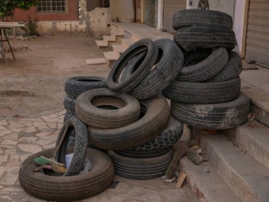 Katlanmış eski araba lastikleri yola yakın yerde, arka planda..