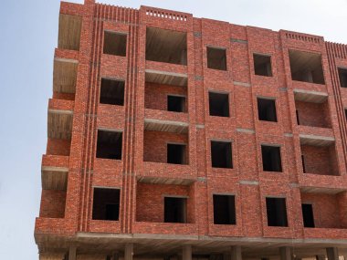 İnşaat halindeki panoramik pencereli kırmızı tuğlalı bina bloğu. 