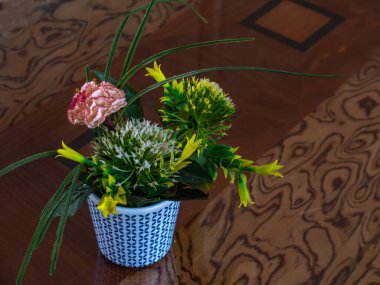 Masanın üzerinde suni çiçekli bir tencere var..