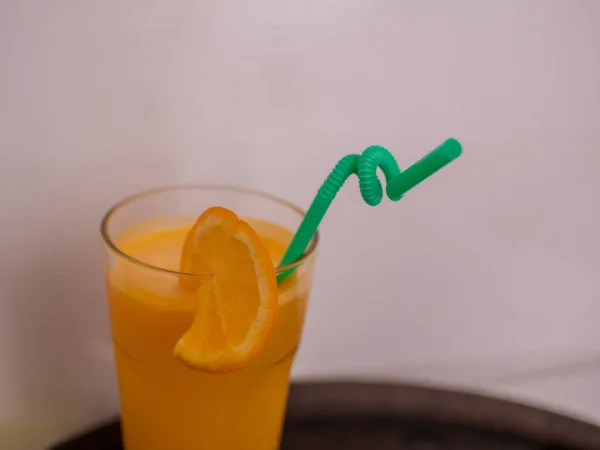 A glass of orange juice with an orange slice and a straw. — Stockfoto