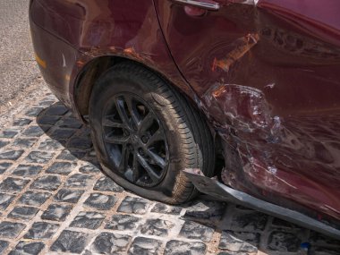 Car accident. A flat tire and a dented car body.